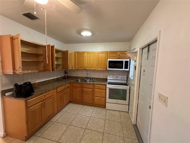 kitchen featuring visible vents, decorative backsplash, dark countertops, white electric range, and a sink