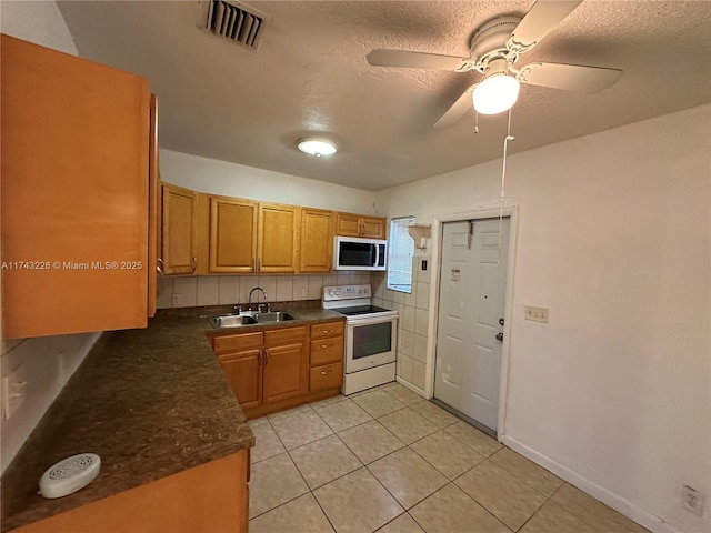 kitchen featuring dark countertops, white electric range, a sink, and visible vents