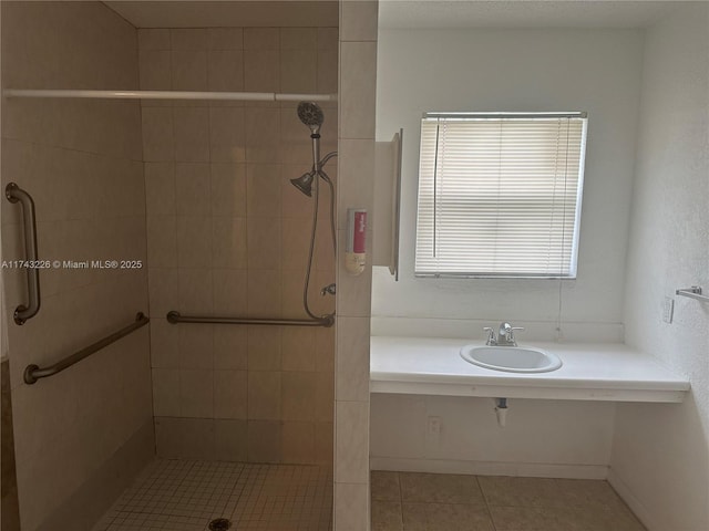 bathroom with tiled shower, a sink, and tile patterned floors