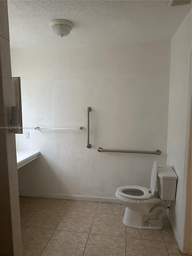 bathroom featuring a textured ceiling, tile patterned flooring, toilet, and baseboards