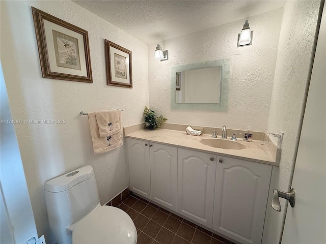 bathroom featuring tile patterned flooring, vanity, a textured ceiling, and toilet