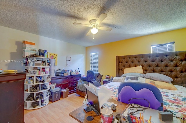 bedroom featuring multiple windows, a textured ceiling, ceiling fan, and light wood-type flooring