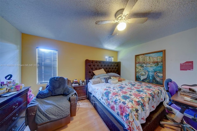 bedroom featuring ceiling fan, a textured ceiling, and light wood-type flooring