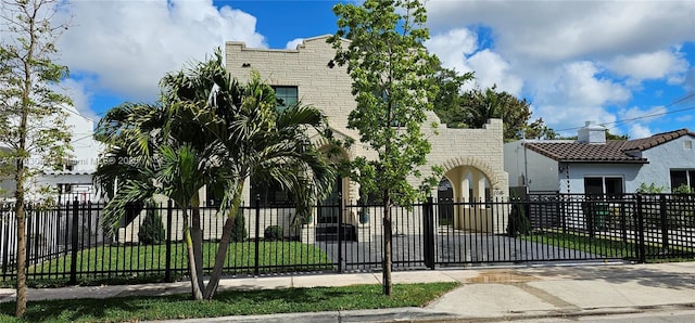 view of front facade with a fenced front yard, stucco siding, a front yard, and a gate