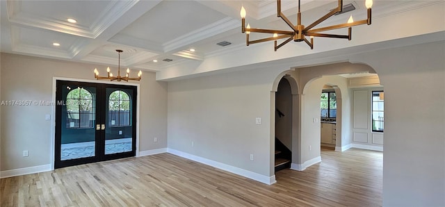 unfurnished room featuring light wood-type flooring, beam ceiling, a notable chandelier, coffered ceiling, and arched walkways