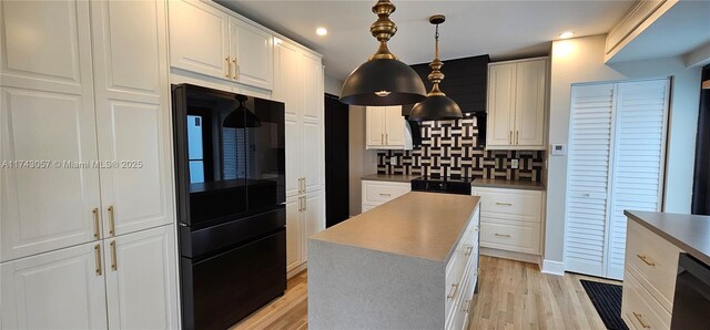 kitchen featuring white cabinetry, light wood-style flooring, tasteful backsplash, and freestanding refrigerator