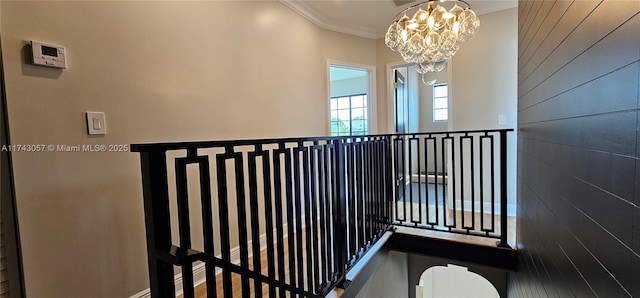 stairs featuring crown molding, wooden walls, and a chandelier