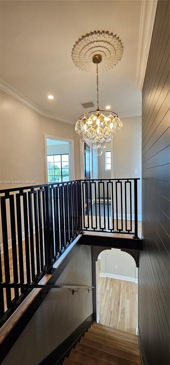 staircase with visible vents, baseboards, wood finished floors, and crown molding