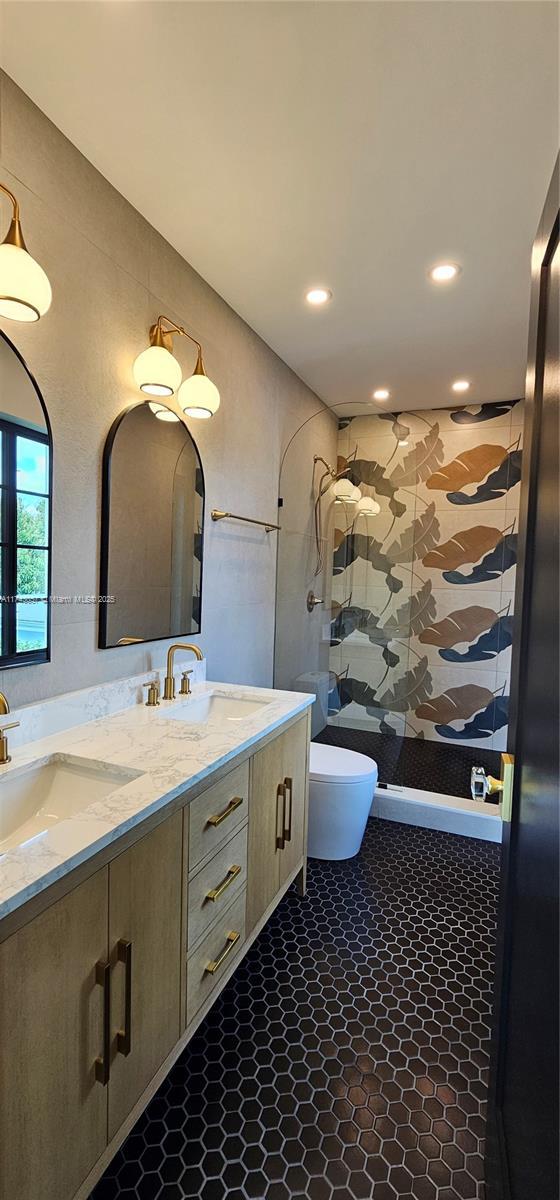 full bath featuring double vanity, a shower stall, toilet, and a sink