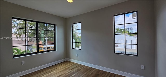 unfurnished room with baseboards and wood finished floors