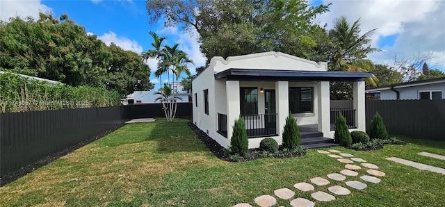 view of front of property with stucco siding, a porch, a front yard, and fence