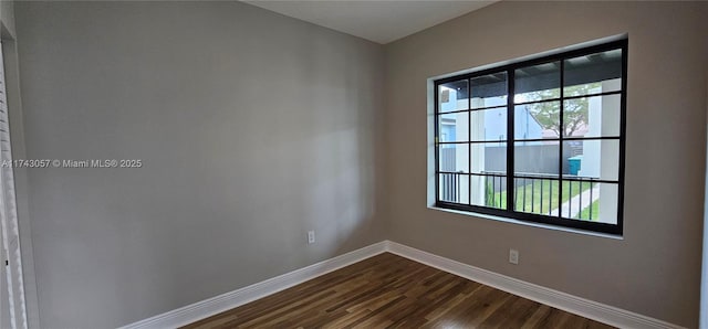 spare room with dark wood finished floors and baseboards