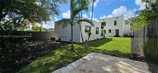 rear view of property featuring fence, a lawn, and stucco siding