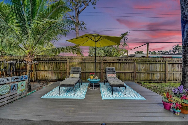 deck at dusk featuring a fenced backyard