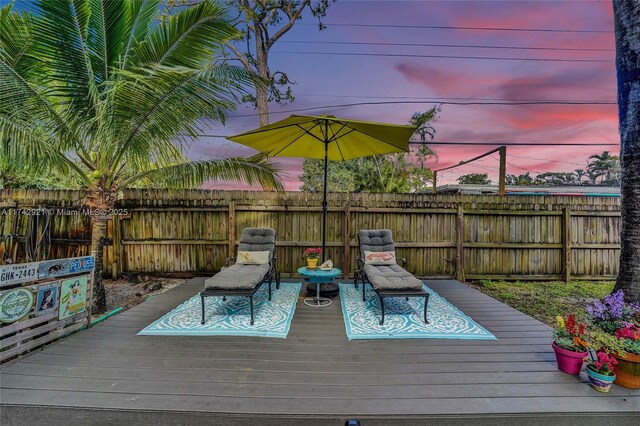 deck at dusk featuring a fenced backyard