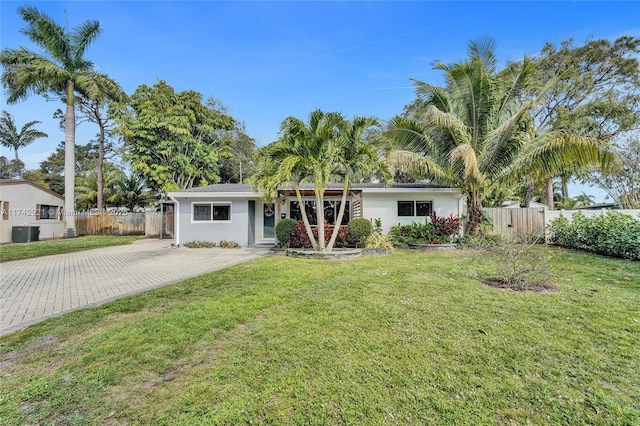 ranch-style house featuring decorative driveway, a front yard, fence, and central air condition unit