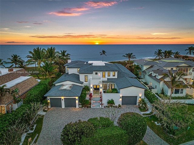 view of front facade featuring a water view, a garage, and solar panels