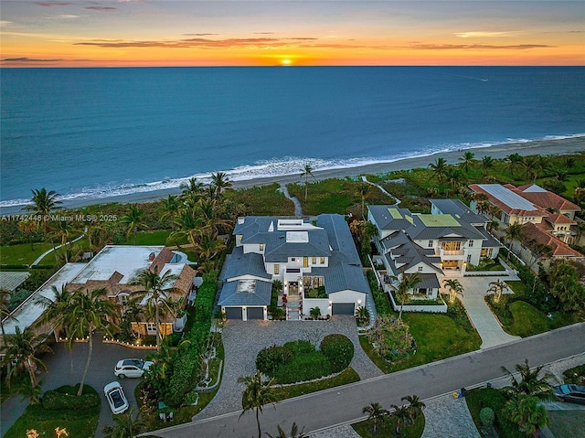 aerial view at dusk with a water view and a view of the beach