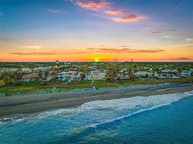 aerial view at dusk with a water view and a view of the beach