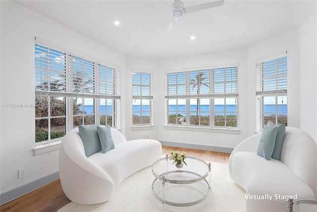 living area with wood-type flooring, a healthy amount of sunlight, and a water view