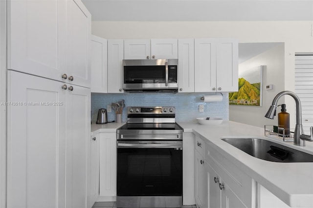 kitchen featuring white cabinetry, stainless steel appliances, sink, and backsplash