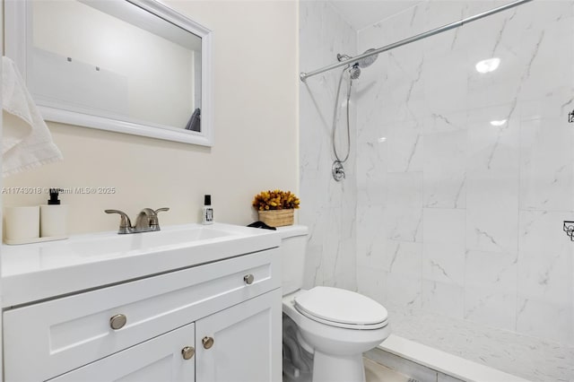 bathroom featuring vanity, a tile shower, and toilet