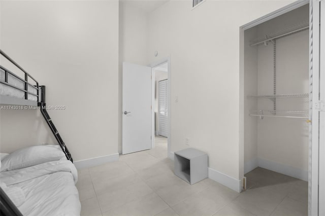 tiled bedroom featuring a closet and a high ceiling