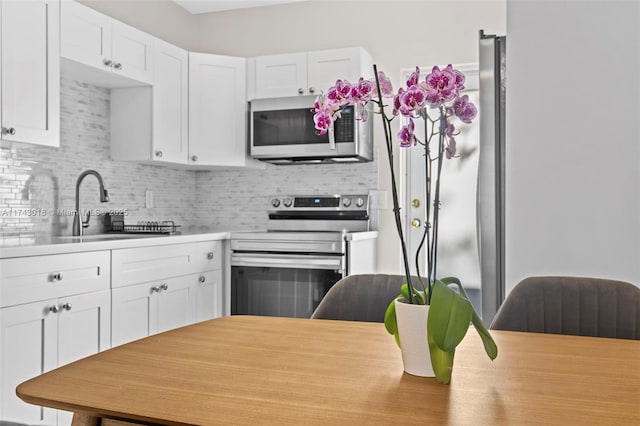 kitchen featuring stainless steel appliances, white cabinetry, tasteful backsplash, and sink