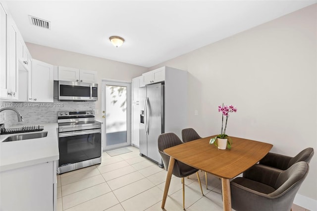 kitchen with appliances with stainless steel finishes, sink, white cabinets, and backsplash