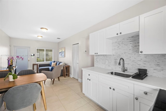 kitchen featuring white cabinetry, sink, decorative backsplash, and light tile patterned floors