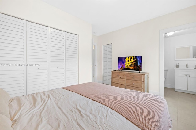 tiled bedroom with connected bathroom, sink, and a closet