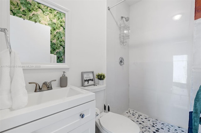 bathroom featuring vanity, toilet, and a tile shower