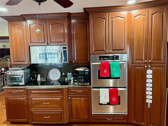kitchen with ceiling fan, appliances with stainless steel finishes, decorative backsplash, and dark stone counters