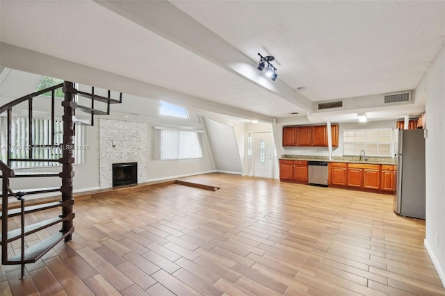 kitchen with appliances with stainless steel finishes, a fireplace, and light wood-type flooring