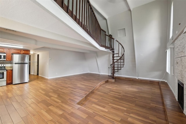 foyer featuring a stone fireplace, light hardwood / wood-style floors, and a high ceiling