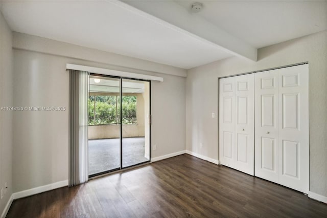 unfurnished bedroom with beamed ceiling, access to exterior, dark hardwood / wood-style flooring, and a closet