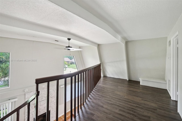 hall with dark hardwood / wood-style flooring, beam ceiling, and a textured ceiling