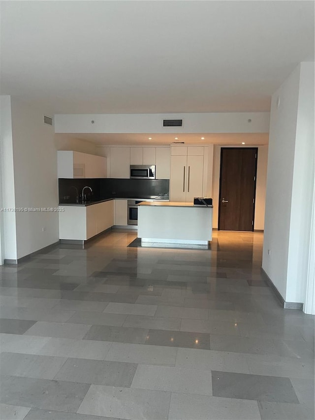 kitchen with sink, decorative backsplash, white cabinets, and appliances with stainless steel finishes