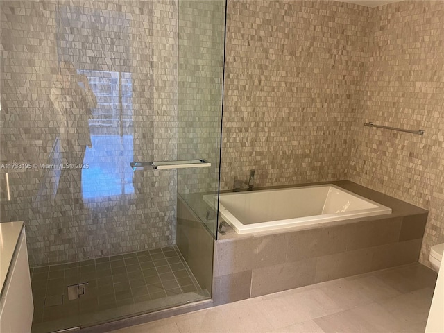 bathroom featuring tile patterned flooring, toilet, independent shower and bath, and tile walls