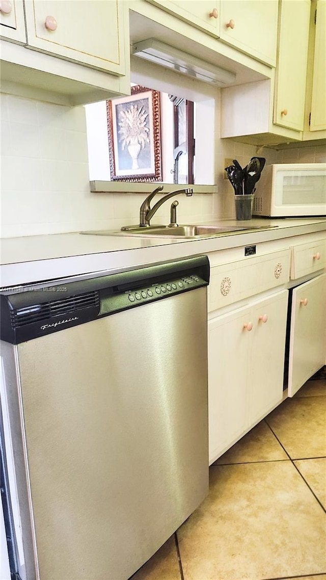 kitchen with tasteful backsplash, dishwasher, and light tile patterned floors