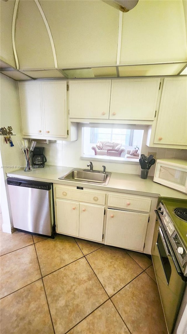 kitchen with white cabinetry, sink, stove, stainless steel dishwasher, and light tile patterned floors