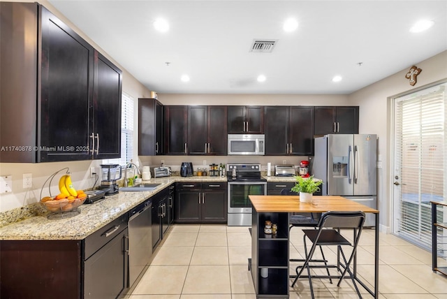 kitchen with sink, dark brown cabinets, light tile patterned flooring, and appliances with stainless steel finishes