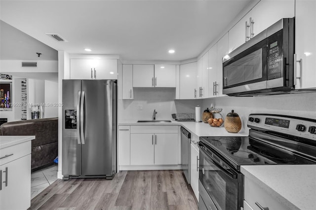 kitchen featuring white cabinetry, sink, stainless steel appliances, and light hardwood / wood-style floors