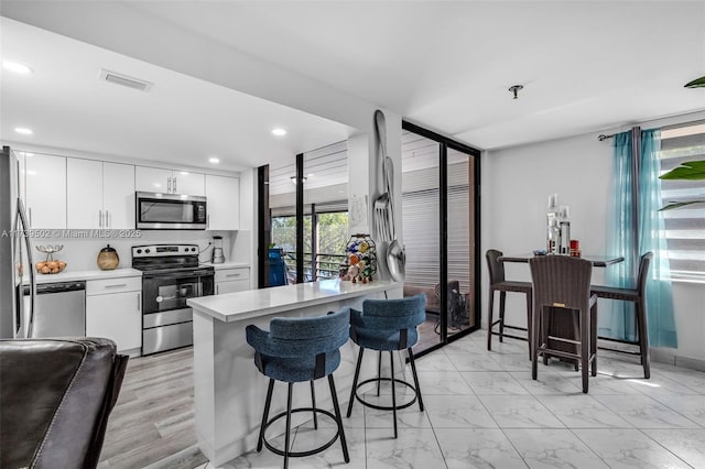 661 NE 195th St Unit 312, Miami, FL 33179 - kitchen with white cabinetry, stainless steel appliances, and a kitchen bar
