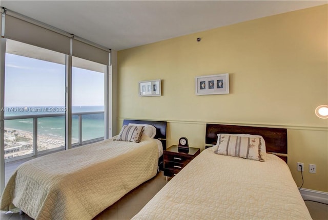 bedroom with a view of the beach, a wall of windows, and a water view