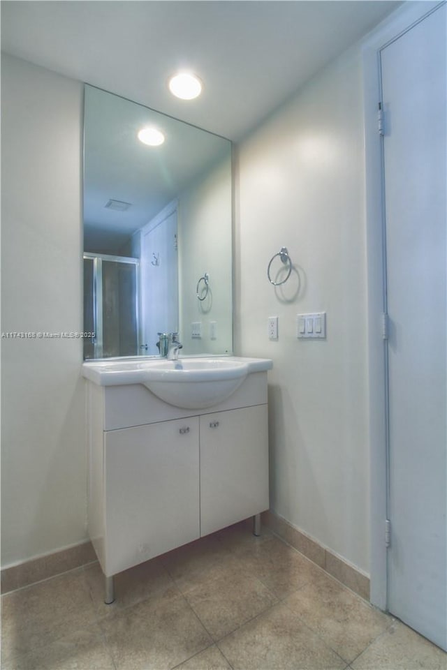 bathroom featuring a shower with door and vanity