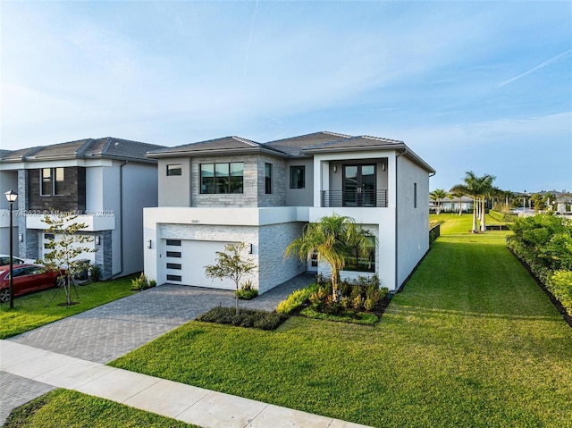 view of front of home featuring a garage, stucco siding, decorative driveway, and a front yard