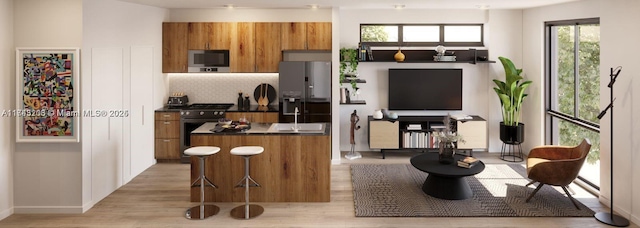 kitchen featuring stainless steel appliances, a kitchen island, light wood-type flooring, and decorative backsplash