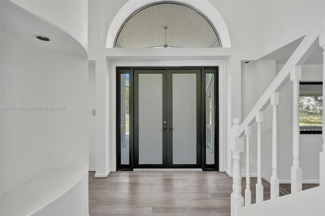 entryway with a towering ceiling, wood-type flooring, and french doors