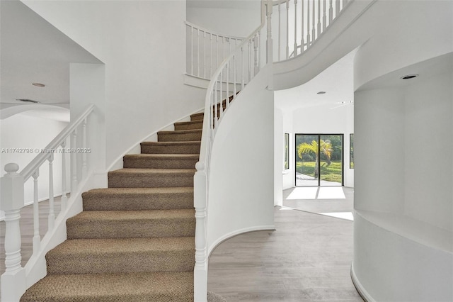 stairs featuring a towering ceiling and hardwood / wood-style floors